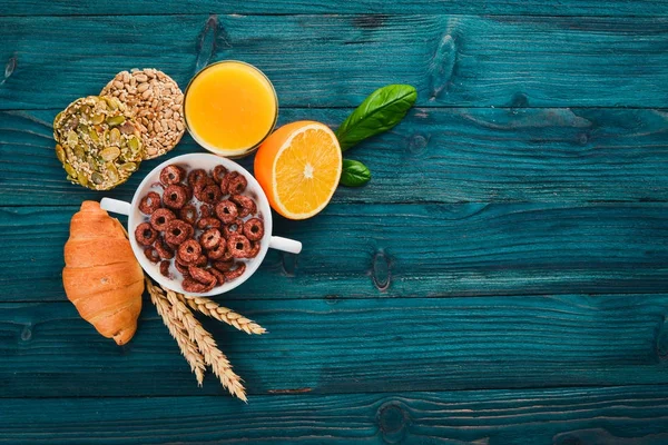 Fitness breakfast, muesli, milk, fruits, nuts and seeds, on a wooden surface. Top view. Free space for text.