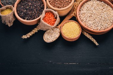 Kabuğu çıkarılmış tane ve tahıl kümesi. Buğday, mercimek, pirinç, darı, arpa, Mısır, siyah pirinç. Siyah bir arka plan üzerinde. Üstten Görünüm. Kopya alanı.