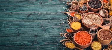 Kabuğu çıkarılmış tane ve tahıl kümesi. Buğday, mercimek, pirinç, darı, arpa, Mısır, siyah pirinç. Mavi ahşap arka plan üzerinde. Üstten Görünüm. Kopya alanı.