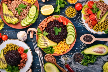 Sağlıklı gıda. Siyah pirinç, buğday, avokado, domates, yeşil bezelye ve fındık. Ahşap bir arka plan üzerinde. Üstten Görünüm. Metniniz için boş alan.