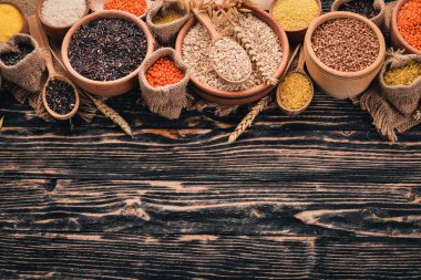 Kabuğu çıkarılmış tane ve tahıl kümesi. Buğday, mercimek, pirinç, darı, arpa, Mısır, siyah pirinç. Ahşap bir arka plan üzerinde. Üstten Görünüm. Kopya alanı.