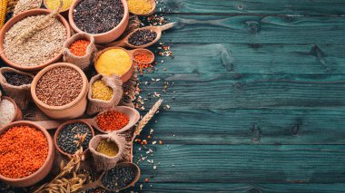 Kabuğu çıkarılmış tane ve tahıl kümesi. Buğday, mercimek, pirinç, darı, arpa, Mısır, siyah pirinç. Mavi ahşap arka plan üzerinde. Üstten Görünüm. Kopya alanı.