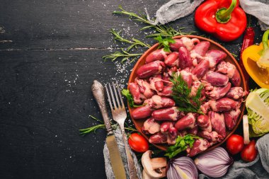 Çiğ tavuk kupa rosemary ile yemek pişirmek için hazır plaka üzerinde ve üzerinde baharat siyah ahşap arka plan. Üstten Görünüm. Metin için boş alan.