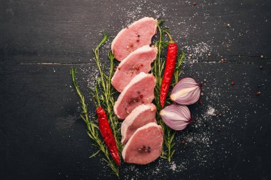 Çiğ et. Biberiye ve baharat siyah ahşap zemin sığır eti biftek. Üstten Görünüm. Metin için boş alan.