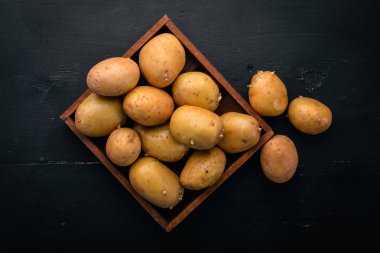 Çiğ patates siyah ahşap zemin. Yemek. Metin için özgür yer. Üstten Görünüm.