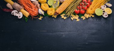 Bir makarna, erişte, makarna, tagliatelle, fettuccine, dizi Farfalle. İtalyan yemek, taze sebze ve baharat. Siyah ahşap arka plan üzerinde. Üstten Görünüm. Kopya alanı.