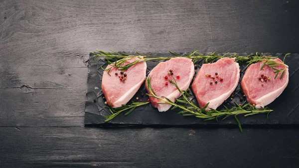 生の肉 ステーキ ローズマリーと黒の木製の背景にスパイスを 平面図です テキスト用の空き容量 — ストック写真