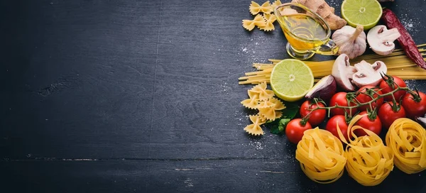 パスタ ラーメン スパゲッ ティー タリアテッレ フェットチーネのファルファッレ イタリア料理 新鮮な野菜やスパイス 木製黒地 平面図です — ストック写真