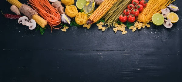 Bir makarna, erişte, makarna, tagliatelle, fettuccine, dizi Farfalle. İtalyan yemek, taze sebze ve baharat. Siyah ahşap arka plan üzerinde. Üstten Görünüm. Kopya alanı.