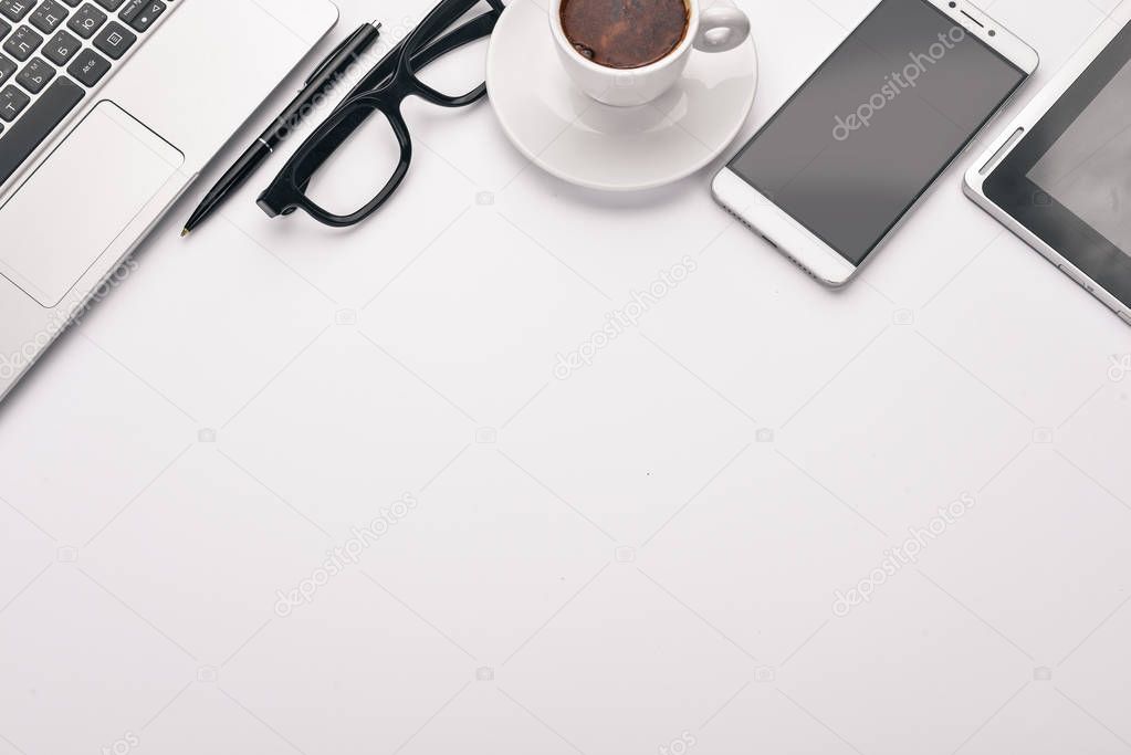 White Office Desk. Laptop, phone, cup of coffee, glasses, pen, pencil. On a white background. Top view. Free space for text.