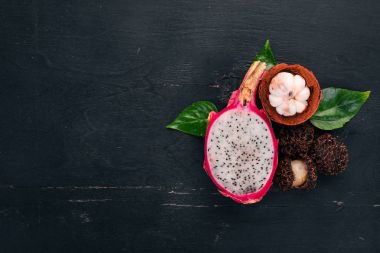Dragon fruit, rambutan and mangosteen. Fresh Tropical Fruits. On a wooden background. Top view. Copy space. clipart