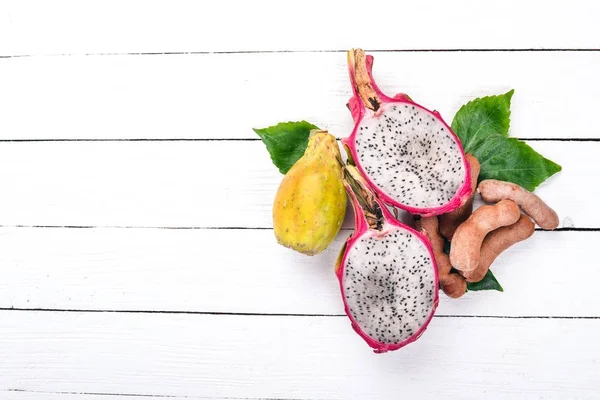 Dragon fruit, cactus fruit and rambutan. Fresh Tropical Fruits. On a wooden background. Top view. Copy space.