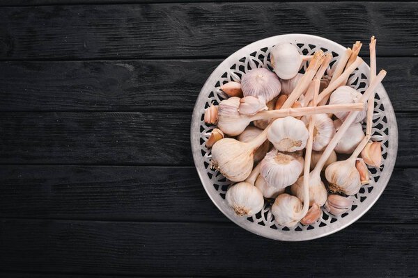 Garlic on a plate. Fresh garlic on a wooden background. Top view. Copy space.