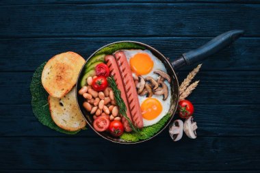 Tam İngiliz kahvaltısı kızarmış yumurta, sosis, fasulye, tost ve kahve kopya alan arka plan üzerinde. Siyah bir ahşap arka plan üzerinde.