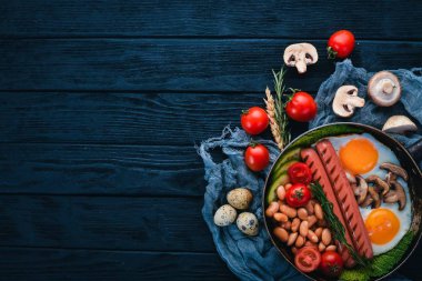 Tam İngiliz kahvaltısı kızarmış yumurta, sosis, fasulye, tost ve kahve kopya alan arka plan üzerinde. Siyah bir ahşap arka plan üzerinde.