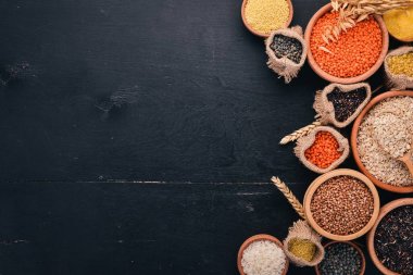 Kabuğu çıkarılmış tane ve tahıl kümesi. Buğday, mercimek, pirinç, darı, arpa, Mısır, siyah pirinç. Siyah bir arka plan üzerinde. Üstten Görünüm. Kopya alanı.