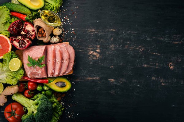 Здоровое питание. Сырое мясо, авокадо, брокколи, свежие овощи, орехи и фрукты. На деревянном фоне. Вид сверху. Копирование пространства
.