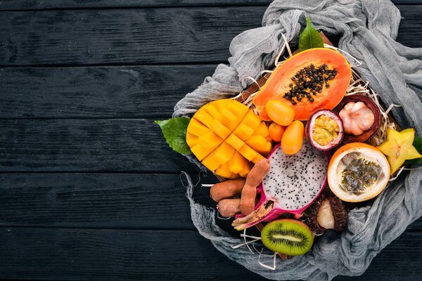Фруктовый дракон, папайя, маракуя, киви, манго и гранадилья в деревянной коробке. Свежие тропические фрукты. На деревянном фоне. Вид сверху. Копирование пространства
.