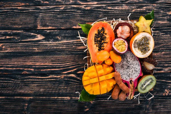 Фруктовый дракон, папайя, маракуя, киви, манго и гранадилья в деревянной коробке. Свежие тропические фрукты. На деревянном фоне. Вид сверху. Копирование пространства
.