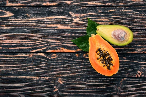 Papaya and avocado. Fresh Tropical Fruits. On a wooden background. Top view. Copy space.