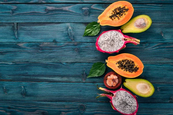 Dragon Fruit, Avocado, Papaya and Mangosteen. Tropical Fruits. On a wooden background. Top view. Copy space.