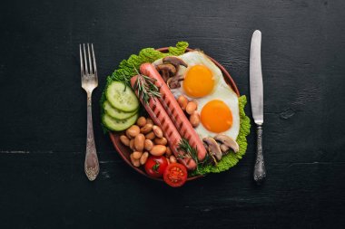 İngiliz kahvaltısı. Kızarmış yumurta, sosis, pastırma, fasulye, tost, domates, kahve fincanı taştan masada. Metin alanı olan Üstten Görünüm