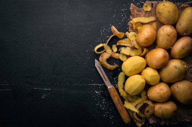 Çiğ patates siyah ahşap zemin. Yemek. Metin için özgür yer. Üstten Görünüm.
