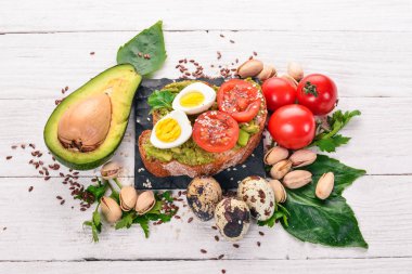 Bıldırcın yumurtası, avokado, domates ve antep fıstığı ile sandviç. Ahşap bir arka plan üzerinde. Üstten Görünüm. Metniniz için boş alan.