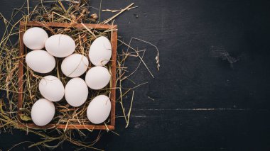Tavuk ahşap sepet içinde çiğ yumurta. Ahşap bir arka plan üzerinde. Üstten Görünüm. Kopya alanı.