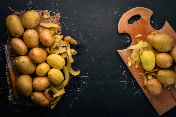 Raw potatoes on a black wooden background. Cooking. Free space for text. Top view.