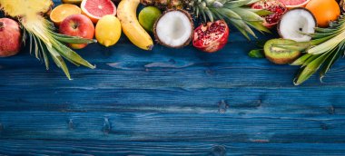 Taze tropikal meyve. Ananas, Hindistan cevizi, kivi, portakal, nar, greyfurt. Ahşap bir arka plan üzerinde. Üstten Görünüm. Metin için boş alan.