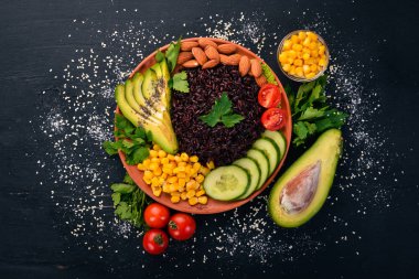 Siyah pirinç, avokado, salatalık, Mısır ve badem. Ahşap bir arka plan üzerinde. Üstten Görünüm. Metniniz için boş alan.
