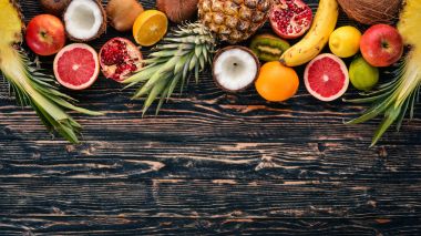 Taze tropikal meyve. Ananas, Hindistan cevizi, kivi, portakal, nar, greyfurt. Ahşap bir arka plan üzerinde. Üstten Görünüm. Metin için boş alan.