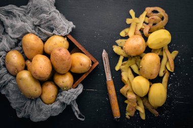 Çiğ patates siyah ahşap zemin. Yemek. Metin için özgür yer. Üstten Görünüm.