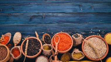 Kabuğu çıkarılmış tane ve tahıl kümesi. Buğday, mercimek, pirinç, darı, arpa, Mısır, siyah pirinç. Mavi ahşap arka plan üzerinde. Üstten Görünüm. Kopya alanı.