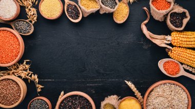 Kabuğu çıkarılmış tane ve tahıl kümesi. Buğday, mercimek, pirinç, darı, arpa, Mısır, siyah pirinç. Siyah bir arka plan üzerinde. Üstten Görünüm. Kopya alanı.