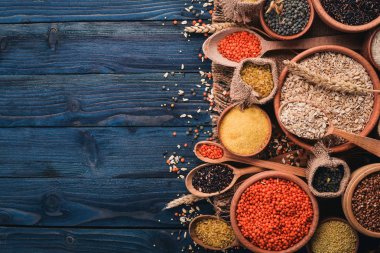 Kabuğu çıkarılmış tane ve tahıl kümesi. Buğday, mercimek, pirinç, darı, arpa, Mısır, siyah pirinç. Mavi ahşap arka plan üzerinde. Üstten Görünüm. Kopya alanı.
