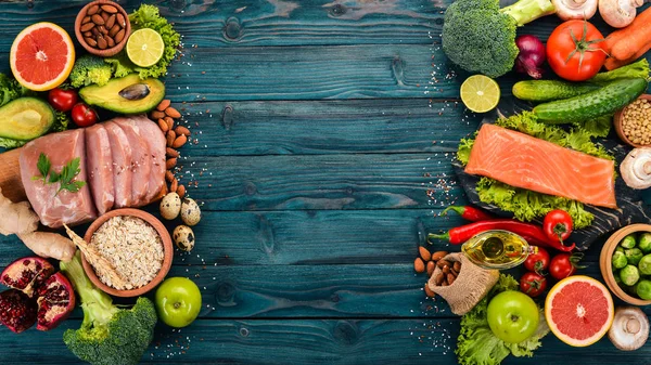 Sağlıklı gıda arka plan. Sağlıklı gıda, tavuk fileto, çiğ et, balık, avokado, brokoli, taze sebze, fındık ve meyve kavramı. Ahşap bir arka plan üzerinde. Üstten Görünüm. Kopya alanı.