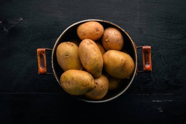 Çiğ patates siyah ahşap zemin. Yemek. Metin için özgür yer. Üstten Görünüm.