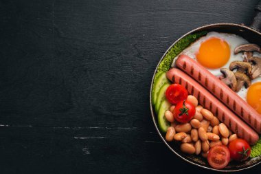 İngiliz kahvaltısı. Kızarmış yumurta, sosis, pastırma, fasulye, tost, domates, kahve fincanı taştan masada. Metin alanı olan Üstten Görünüm