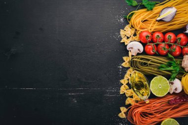 Bir makarna, erişte, makarna, tagliatelle, fettuccine, dizi Farfalle. İtalyan yemek, taze sebze ve baharat. Siyah ahşap arka plan üzerinde. Üstten Görünüm. Kopya alanı.