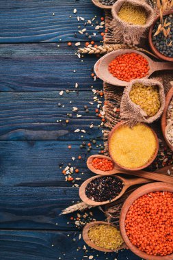 Kabuğu çıkarılmış tane ve tahıl kümesi. Buğday, mercimek, pirinç, darı, arpa, Mısır, siyah pirinç. Mavi ahşap arka plan üzerinde. Üstten Görünüm. Kopya alanı.