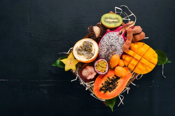 Fruit dragon, papaya, maracuya, kiwi, mango and granadilla in a wooden box. Fresh Tropical Fruits. On a wooden background. Top view. Copy space.