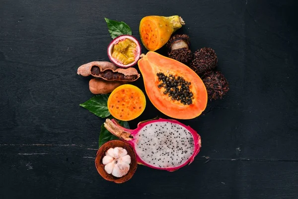 Papaya, Dragon Fruit, Cactus Fruit. Fresh Tropical Fruits. On a wooden background. Top view. Copy space.