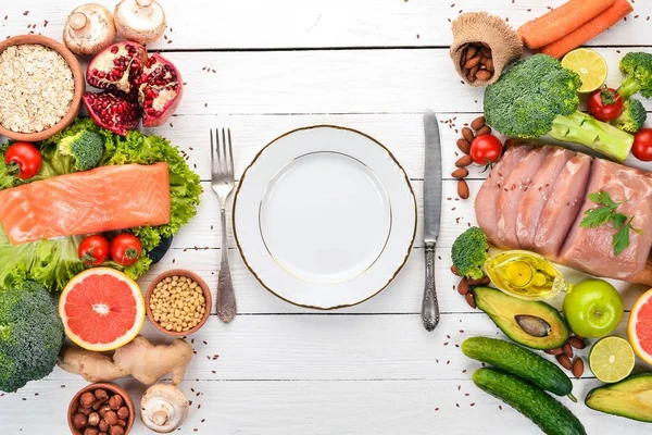 Healthy food background. Concept of Healthy Food, Chicken Fillet, Raw Meat, Fish, Avocado, Broccoli, Fresh Vegetables, Nuts and Fruits. On a wooden background. Top view. Copy space.