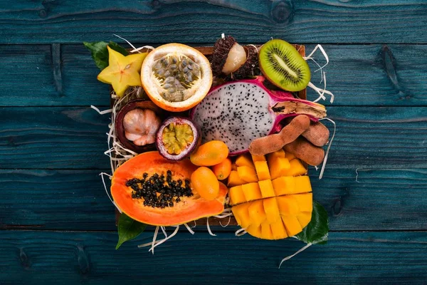 Fruit dragon, papaya, maracuya, kiwi, mango and granadilla in a wooden box. Fresh Tropical Fruits. On a wooden background. Top view. Copy space.