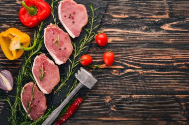 Çiğ et. Biberiye ve baharat siyah ahşap zemin sığır eti biftek. Üstten Görünüm. Metin için boş alan.