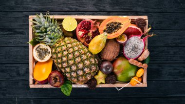 Tahta bir kutuda tropik meyve. Papaya, Dragon Fruit, rambutan, tamarind, kaktüs meyvesi, avokado, granadilla, carambola, kumquat, mango, mangosteen, tutku meyvesi, hindistan cevizi.