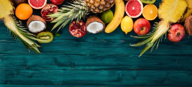 Taze tropikal meyve. Ananas, Hindistan cevizi, kivi, portakal, nar, greyfurt. Ahşap bir arka plan üzerinde. Üstten Görünüm. Metin için boş alan.