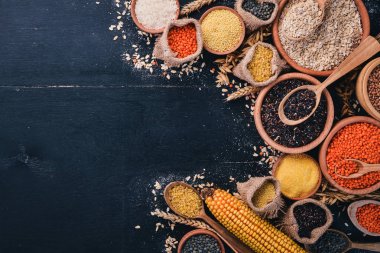 Kabuğu çıkarılmış tane ve tahıl kümesi. Buğday, mercimek, pirinç, darı, arpa, Mısır, siyah pirinç. Siyah bir arka plan üzerinde. Üstten Görünüm. Kopya alanı.